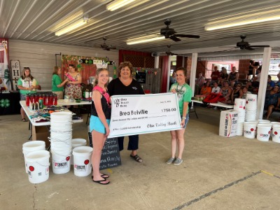 Adults presenting a scholarship check to college recipient.